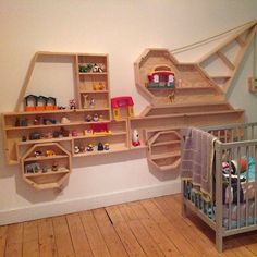 a baby's room with wooden shelves and toys on the wall next to a crib