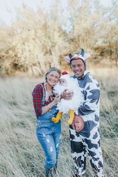 a man and woman dressed up as cows holding a baby in a costume that looks like a cow