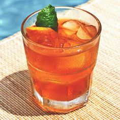 a glass filled with ice sitting on top of a table next to a swimming pool