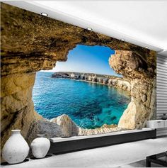 an ocean scene with rocks and water in the foreground, as seen through a window