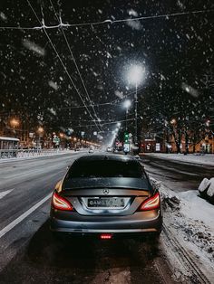 a car is parked on the side of the road in the snow at night time