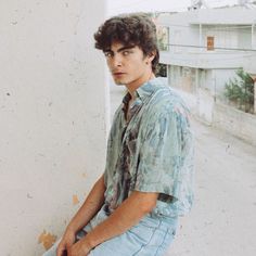 a young man sitting on the side of a building