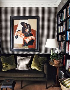 a living room filled with furniture and bookshelves next to a painting on the wall