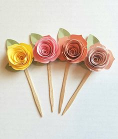 four paper flowers are arranged on wooden sticks