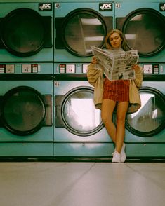 a woman sitting on top of a stack of washers in front of a dryer