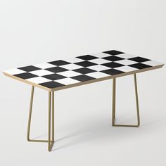 a black and white checkerboard table with gold legs on an off white background