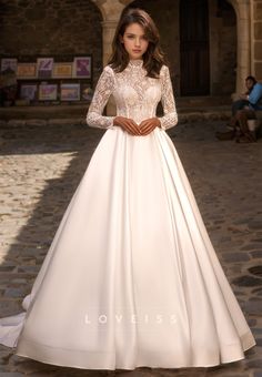 a woman in a white wedding dress standing on a cobblestone street with her hands on her hips