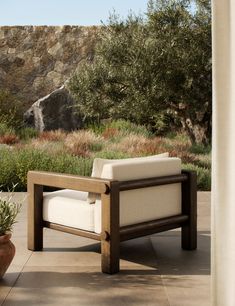 a wooden chair sitting on top of a patio next to a stone wall and trees