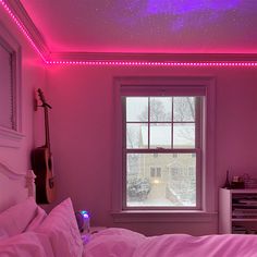 a bedroom with pink walls and purple lights on the ceiling, along with a guitar propped up against the wall