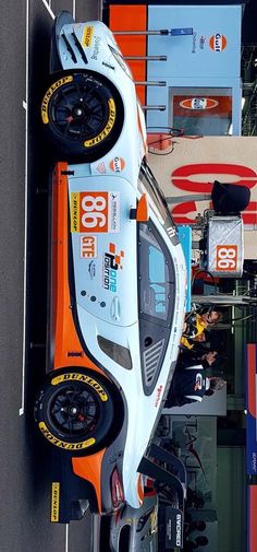 an orange and white race car is parked on the street