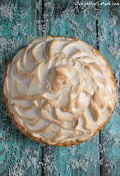 a frosted pie sitting on top of a blue wooden table next to a knife