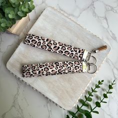 two leopard print hair clips on a white marble surface with green plants in the background