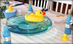 a rubber ducky floating in a bowl on top of a table with blue bottles