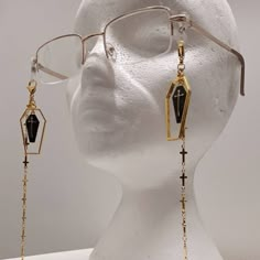 Golden cemetery glasses chain Brand new! Jazz up those spectacles with these beautiful chains. Adorned with gold coffin outline and central black and gold coffin charm, chain is made up of tiny little crosses. Suitable for all glasses types. The elastic loops fit comfortably on your frames without causing damage. Wear them near the front to make a statement or further back on your frames to appear like earrings.  Choose between a black or clear loop connector to connect the chain to your glasses Gothic Glasses Frames, Goth Glasses Chain, Ginkgo Aesthetic, Glasses Chain Aesthetic, Coffin Outline, Fantasy Glasses, Glasses Types, Goth Glasses, Glasses With Chain