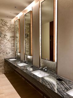 there are four sinks in this bathroom with mirrors on the wall and marble counter tops