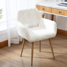 a white chair sitting on top of a hard wood floor next to a desk and window