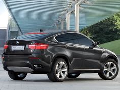 the back end of a black bmw suv parked in front of a building with an awning