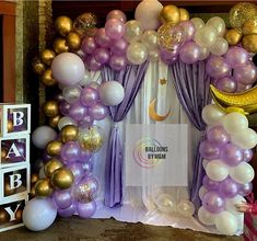 balloon arch with purple and gold balloons for baby shower