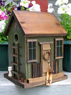 a bird house with flowers in the background