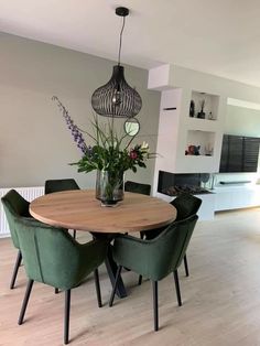 a dining room table with green chairs and a vase filled with flowers on top of it