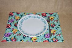 a plate with a fork and knife sitting on top of a floral place mat next to a napkin