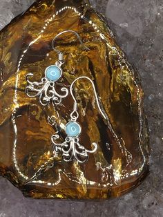 Oh these are the cutest little octopus earrings. The body is a beautiful Larimar round and bezel set. Fun little legs and navy blue enameled eyes. These are handmade by me or my partner in our shop on the island of Kauai in Hawaii. We have been making handmade jewelry for over 20 years. We would love to see you come and visit us but we are just as happy for you to shop a little piece of paradise here on Etsy. Mahalo Whimsical Blue Round Jewelry, Whimsical Round Blue Jewelry, Ocean-inspired Hypoallergenic Jewelry As A Gift, Ocean-inspired Hypoallergenic Jewelry Gift, Silver Ocean-inspired Earrings For Gifts, Ocean-inspired Blue Earrings For Gifts, Whimsical Jewelry With Matching Round Earrings, Whimsical Round Jewelry With Matching Earrings, Sterling Silver Ocean-inspired Earrings With Ear Wire