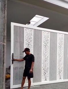 a man is standing in front of a white fence and holding onto the door handle