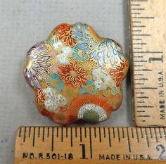 a small flowered glass object next to a ruler