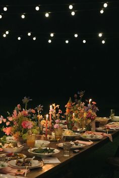 a long table is set with flowers and candles for an outdoor dinner party or social gathering