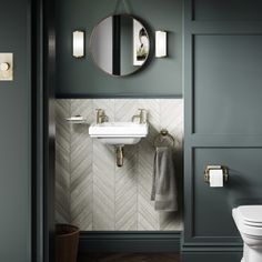 a white toilet sitting next to a bathroom sink under a round mirror on a wall