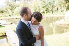 a bride and groom standing next to each other in front of a pond at their wedding