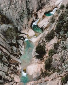 an aerial view of some water in the middle of a rocky mountain side with trees and rocks