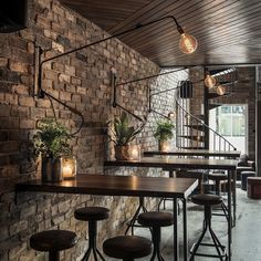 the interior of a restaurant with brick walls and wooden tables, stools and lights