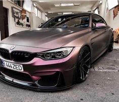 a car parked in front of a building with purple paint on it's hood