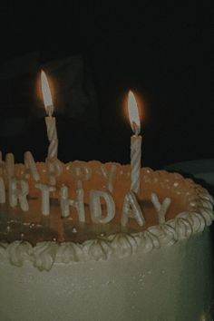 a birthday cake with three lit candles on it's top and the words happy birthday written in white frosting