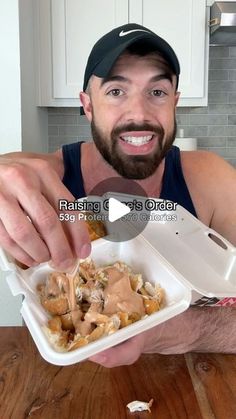 a man is holding a container with food in it and he is smiling at the camera