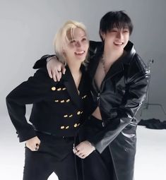 two people are posing for a photo in black clothes and gold buttons on their jackets