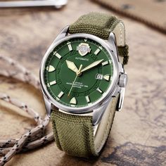 Created to ensure complete accuracy, this military green army watch for men is equipped with the automatic self-wind movement. Designed in a round case made from stainless steel, it comes with a sapphire crystal window that offers maximum protection. Furnished with a canvas band which is secured with a buckle clasp, this water-resist watch even has features like complete calendar and luminous hands. Luxurious but practical, get it now!

Specifications
Brand Name: GeraldBlack
Water Resistance Dep Army Watches, Military Watches, Watch For Men, Mens Luxury, Military Green, Breitling Watch, Sapphire Crystal, Omega Watch, Army Green