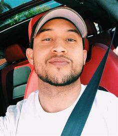 a man sitting in the back seat of a car wearing a baseball cap and suspenders