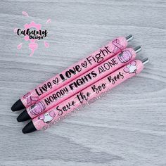 three pink pens with writing on them sitting on top of a wooden table next to each other