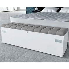 a white bed with a storage bench underneath it