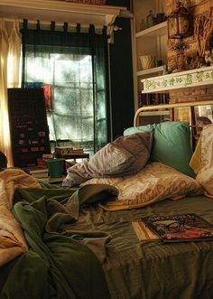 an unmade bed with green sheets and pillows