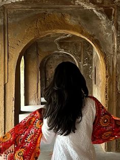 a woman in white shirt and red scarf walking through an archway