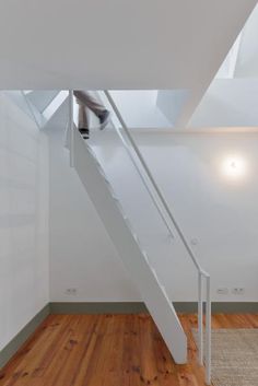 a person is walking up the stairs in a house with white walls and wood floors