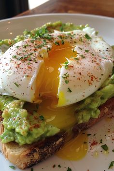 an egg and avocado sandwich is on a white plate with green garnish