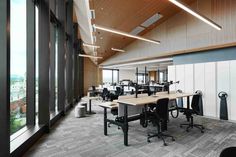 an empty office with lots of desks and chairs in front of large windows overlooking the city