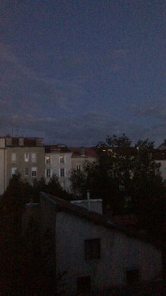 the night sky is dark and cloudy over some buildings