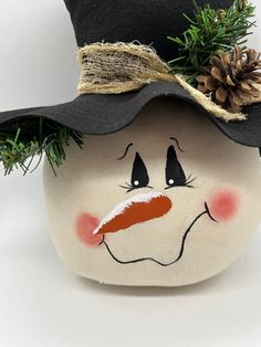 a painted snowman with a black hat and pine cone on its head