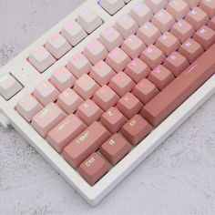 a computer keyboard with pink keys sitting on top of a white table next to a mouse