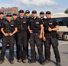 a group of police officers standing next to each other in front of a city bus